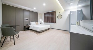 A modern hotel room with a bed, bedside table, chair, and a small table. - Two H Hotel (Busan)