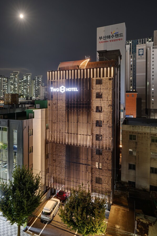 A modern hotel with a prominent 'Two Hotel' sign, surrounded by other buildings and trees. - Two H Hotel (Busan)