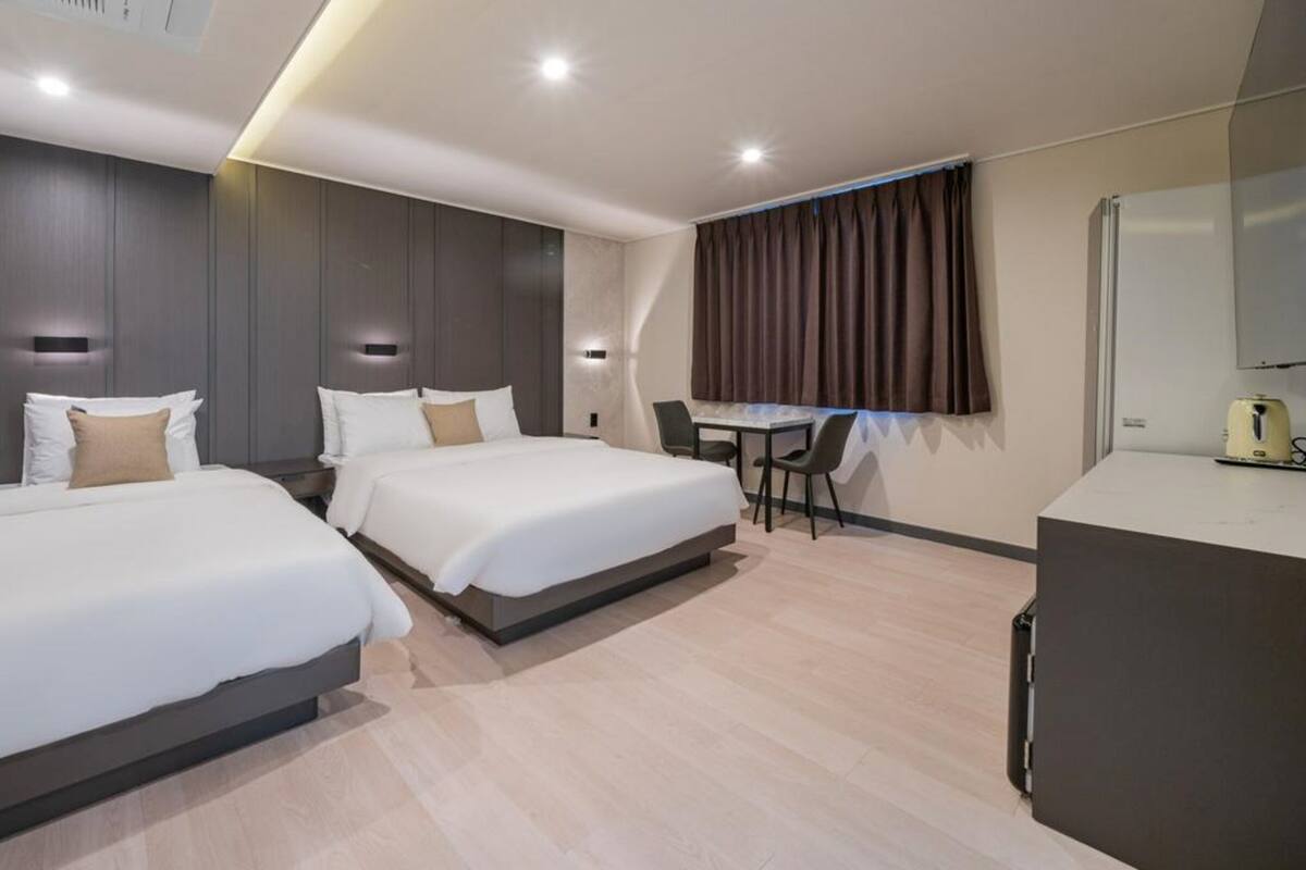 A hotel room with two beds, a desk, and a chair.
