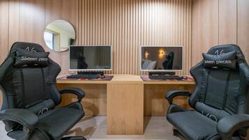 Un espacio de oficina moderno con dos sillas de juego negras con la etiqueta “Sixteen pieces” y un escritorio de madera con dos monitores de computadora.
