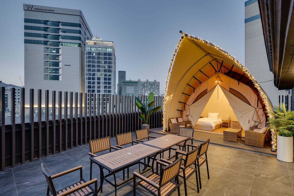 A rooftop terrace with a tented sleeping area, a dining table, and chairs.