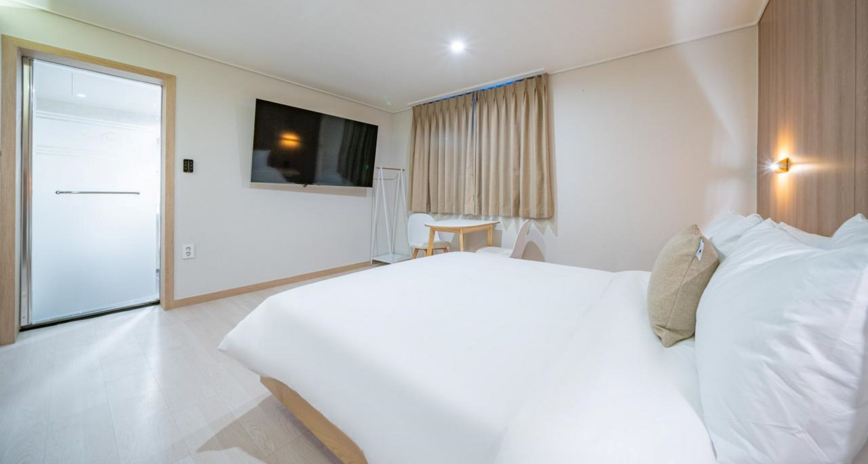 Una habitación de hotel con una cama grande, un escritorio, una silla, un televisor y una cortina.