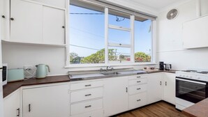 A modern kitchen with white cabinetry, a large window, a built-in oven, and a coffee maker.
