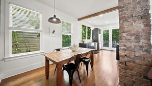 Une cuisine moderne avec une table et des chaises en bois, un luminaire suspendu et un mur en briques.
