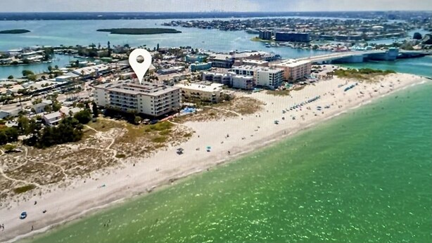 An aerial view of a coastal area with a large hotel complex, a sandy beach, and clear blue waters. - Beachfront Bliss - King Bed - Heated Pool - Steps to John’s Pass & Dining! (Madeira Beach)