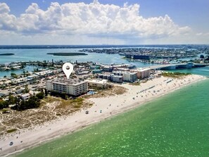 Eine Luftaufnahme einer Küstenregion mit einem großen Hotelkomplex, einem Sandstrand und klarem, blauem Wasser.