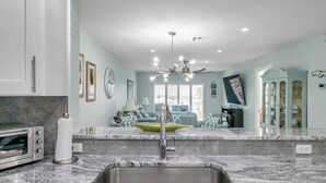 A modern kitchen with a built-in oven, a sink, and a ceiling fan. - Beachfront Bliss - King Bed - Heated Pool - Steps to John’s Pass & Dining! (Madeira Beach)