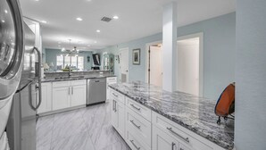 A modern kitchen with white cabinets, granite countertops, and stainless steel appliances. - Beachfront Bliss - King Bed - Heated Pool - Steps to John’s Pass & Dining! (Madeira Beach)