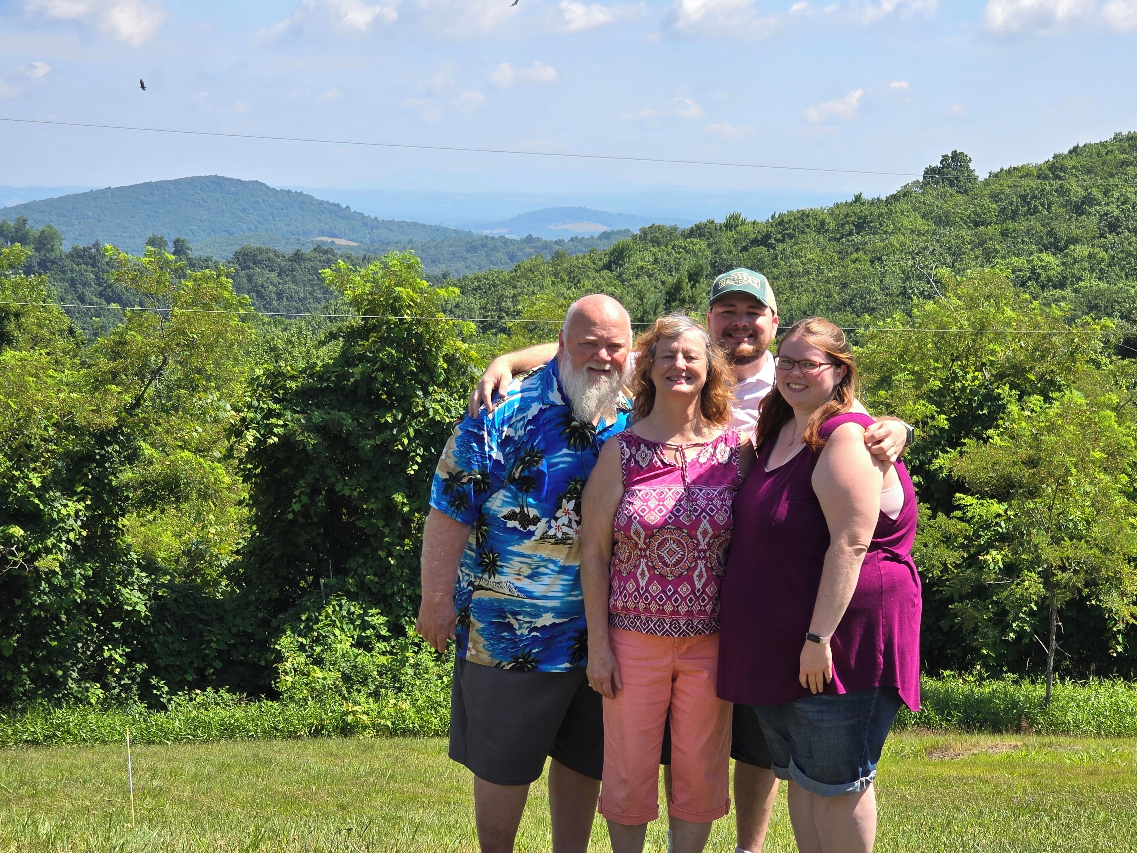 A group of people standing in a grassy area with a mountainous landscape in the background.