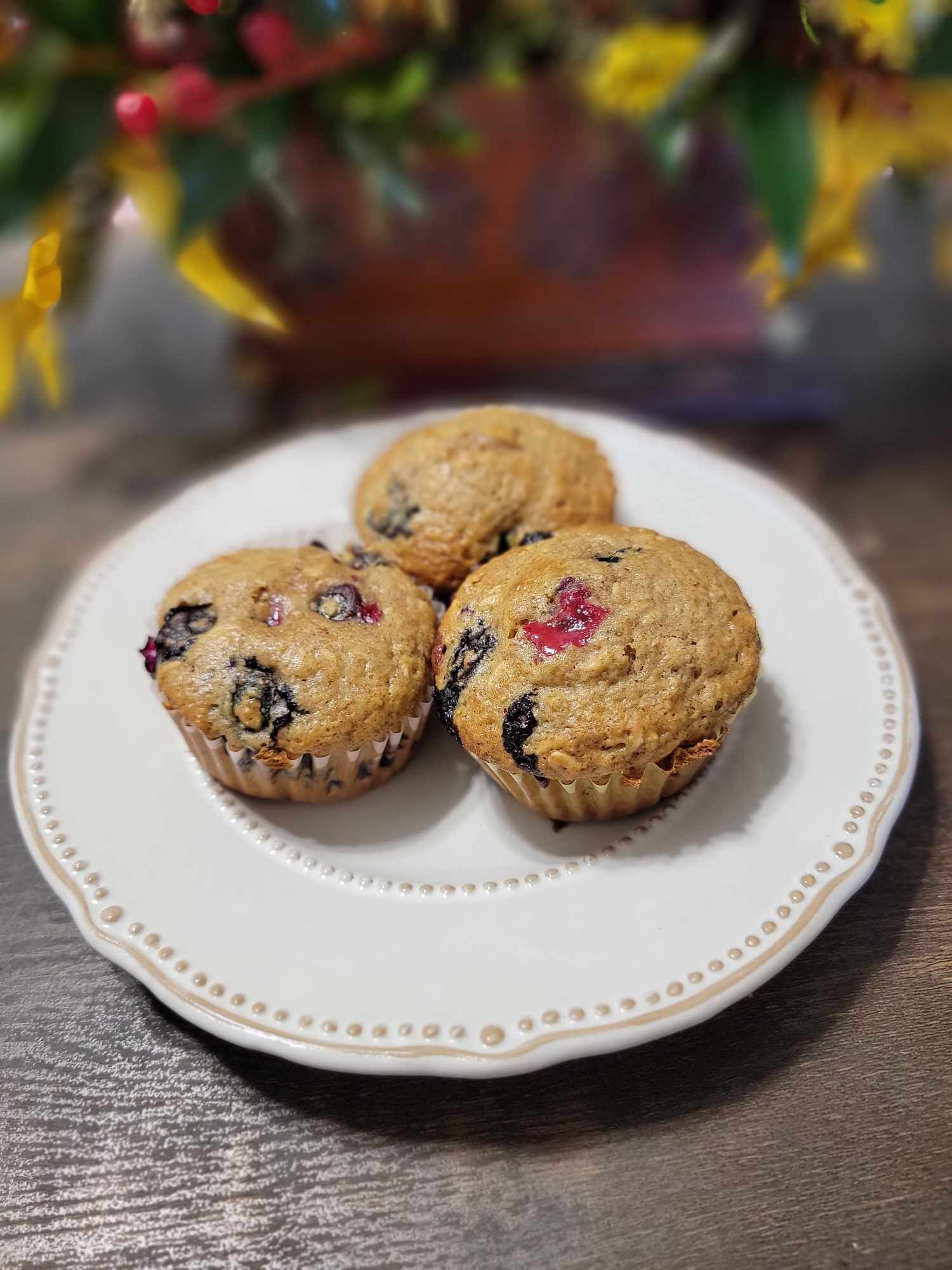 Three muffins on a white plate with a decorative edge.