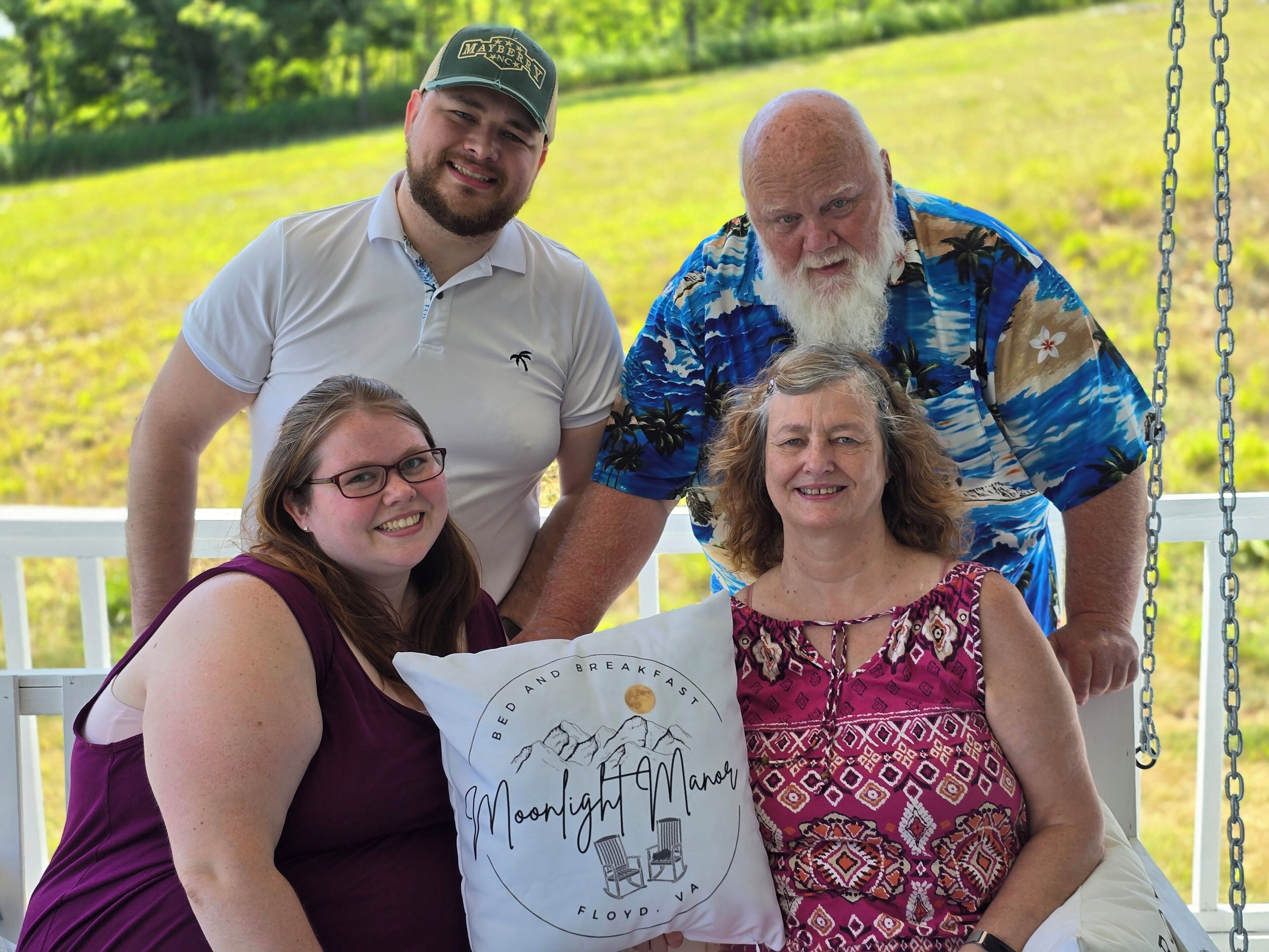 A group of people on a porch with a grassy field in the background.