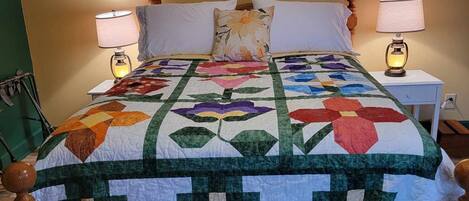 Ein Bett mit einer floralen Stegdecke, zwei Nachttischlampen und einem Holz-Kopfende.