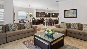 A modern living room with two sofas, a coffee table, and a dining area in the background.