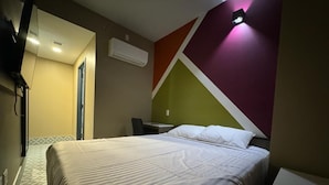 Une chambre d’hôtel équipée d’un lit, d’un bureau et d’un téléviseur fixé au mur.
