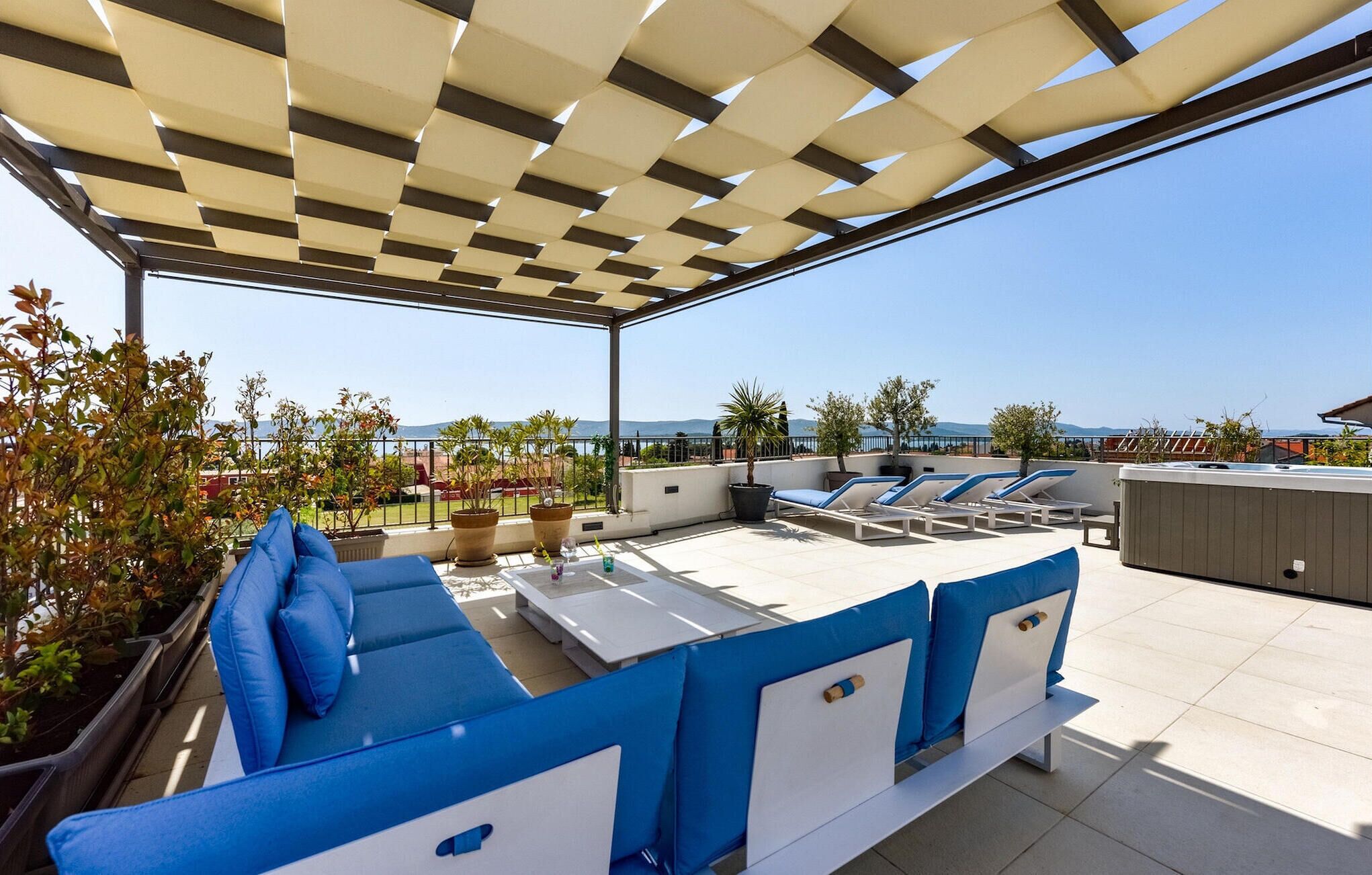 A rooftop terrace with a covered seating area, outdoor tables, and lounge chairs.