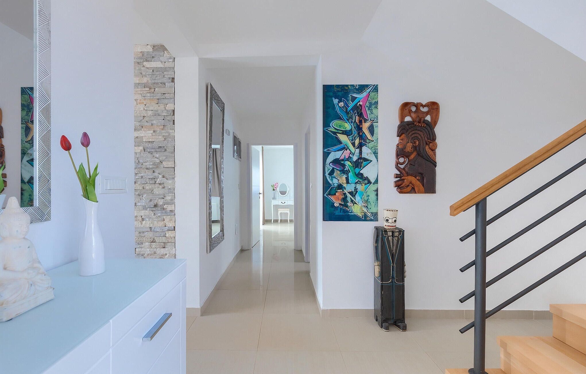 A modern interior with a stone accent wall, a staircase, and artwork on the walls.