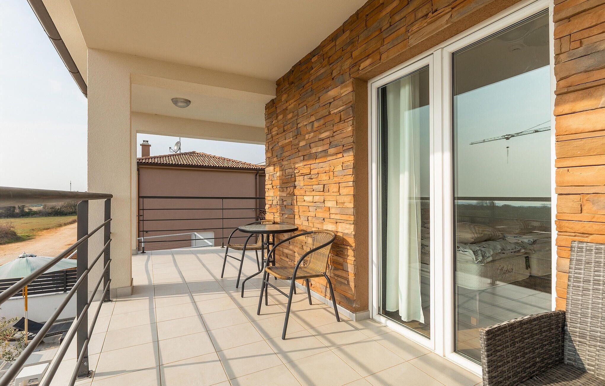 Een balkon met een tafel, stoelen, een glazen deur en uitzicht op een bouwplaats.