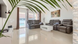 Un salon moderne avec des canapés en cuir, une table basse blanche et une grande plante.