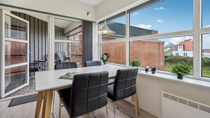 Une cuisine moderne dotée d’une grande fenêtre, un coin repas avec une table et des chaises, et une vue sur l’extérieur.
