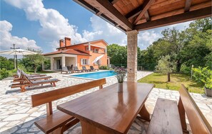 A poolside area with wooden benches and a table, a swimming pool, and a house in the background. - Pet friendly home in Labin - Rabac (Labin - Rabac)