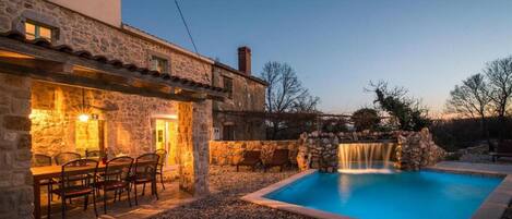A stone building with a pool and a waterfall.