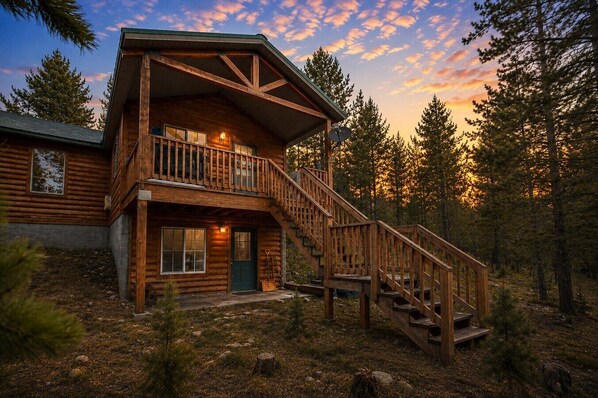 A log cabin with a balcony and a staircase leading to the entrance.