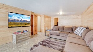 Un salon moderne doté d’un grand téléviseur à écran plat, d’un canapé d’angle et d’un tapis en fourrure.