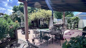 Un patio couvert aménagé avec du mobilier d’extérieur, un barbecue et un jardin.