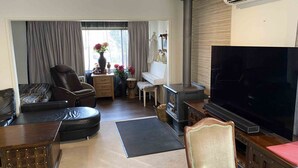 Un salon comprenant un canapé, un fauteuil inclinable, un téléviseur, un piano et une cheminée.