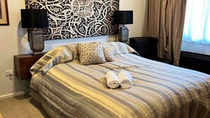 Un lit bien fait, avec une literie à rayures, deux lampes de chevet et un élément décoratif mural au-dessus du lit.