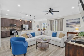 A modern living room with a sectional sofa, a round coffee table, and a blue armchair.