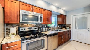 A modern kitchen with wooden cabinets, stainless steel appliances, and a tiled backsplash. - Impeccably maintained Marco Island oasis! (Marco Island)