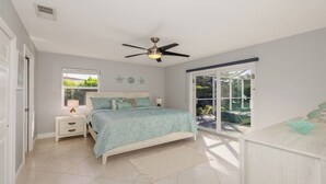 A bedroom with a bed, nightstands, a ceiling fan, a window, and a sliding glass door leading to an outdoor area. - Impeccably maintained Marco Island oasis! (Marco Island)