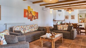 Una sala de estar con un sofá, sillones y una mesa de centro. Hay una chimenea, un comedor y obras de arte en las paredes.