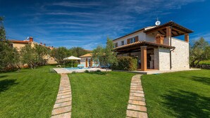 Una casa moderna con piscina, un sendero de piedra y césped cuidado.