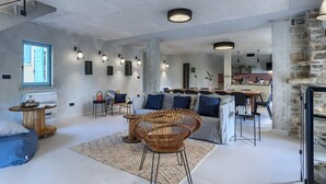 Un vaste espace de vie comprenant un canapé, un fauteuil en osier et une table à manger.