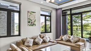 A spacious living room with a large sectional sofa, a coffee table, and a chandelier. - Rosemary Villa near Han River  (Da Nang)