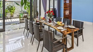 A dining area with a long wooden table, wicker chairs, and a decorative ceiling light. - Rosemary Villa near Han River  (Da Nang)
