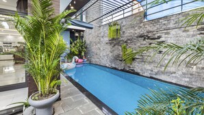 An indoor swimming pool with a glass ceiling, surrounded by potted plants and a brick wall. - Rosemary Villa near Han River  (Da Nang)
