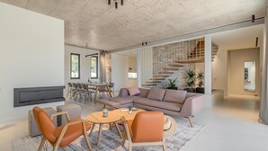 A spacious living area with a large sectional sofa, a dining table with chairs, and a staircase with a glass railing. - Nice home in Primosten (Primosten)