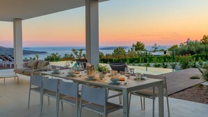 A dining area with a table set for six, overlooking a scenic view of the sea and hills. - Nice home in Primosten (Primosten)