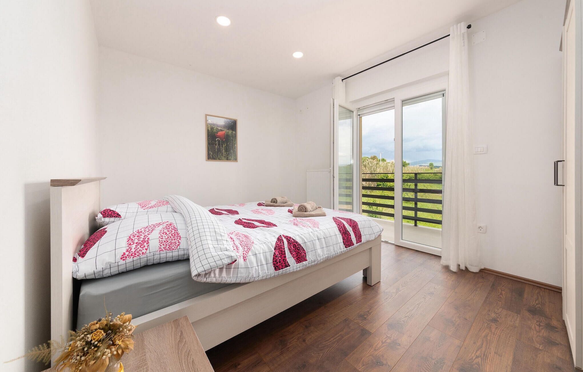 A bedroom with a bed, a window, and a view of greenery outside.