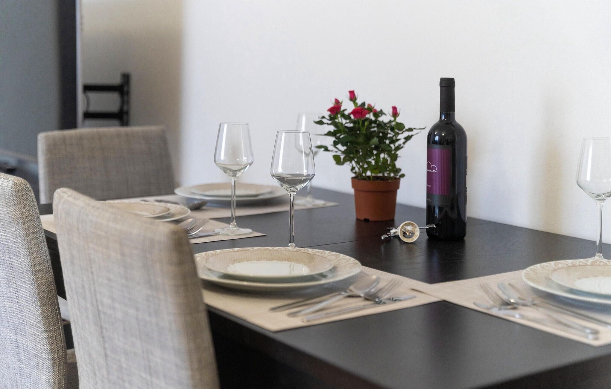 A dining table set for four with plates, cutlery, and wine glasses.