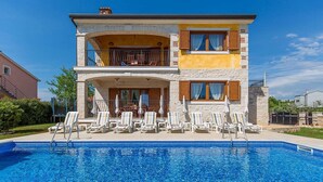 Una casa de dos pisos con piscina delantera.