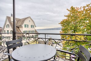 Un balcone con tavolo e sedie che si affaccia su uno specchio d'acqua e edifici.