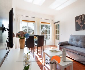 Un salon moderne avec un canapé gris, une table basse blanche et un coin repas comprenant une table et des chaises.