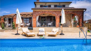 A two-story house with a swimming pool, outdoor seating area, and a stone facade. - Beautiful home in Porec (Porec)