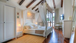 A bedroom with a four-poster bed, a wooden ceiling, a television, and a wicker chair. - Beautiful home in Porec (Porec)