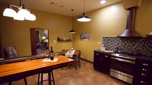 A kitchen with a wooden bar, stainless steel appliances, and pendant lighting.