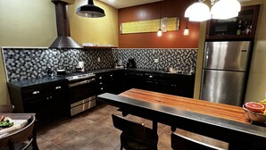 A modern kitchen with a central island, black cabinets, and a stainless steel refrigerator.